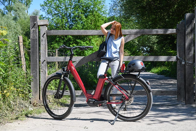 Une femme au près de son vélo électrique dans un chemin de terre