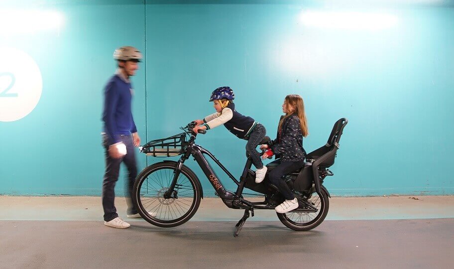 Un père et ses deux enfants avec un vélo électrique cargo