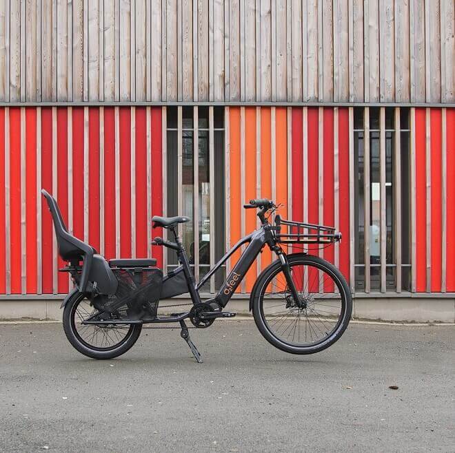 Un vélo électrique cargo garé devant un bâtiment